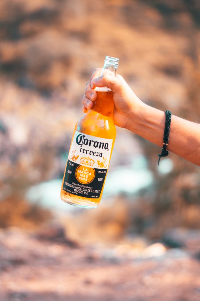 A teen hand holds a beer and alcoholism is complicated by severe chronic depression.